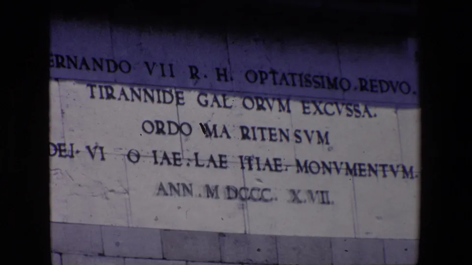 1967 Madrid 8mm frame of a cropped stone inscription where Fernando VII, Latin-style wording, and the 1817 date are partly visible.
