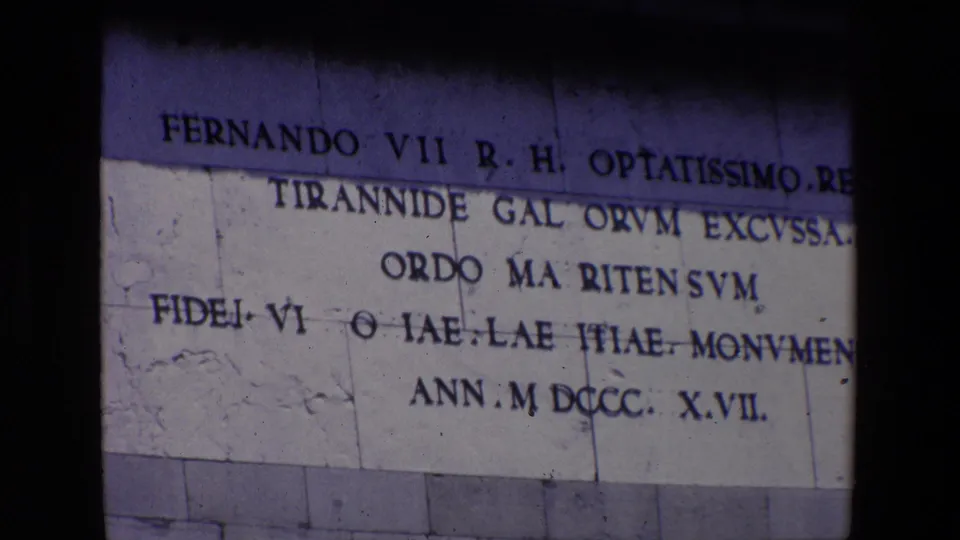 1967 Madrid 8mm frame holding on the monument inscription dedicated to Fernando VII, with Latin-style text and the 1817 date visible on pale stone.