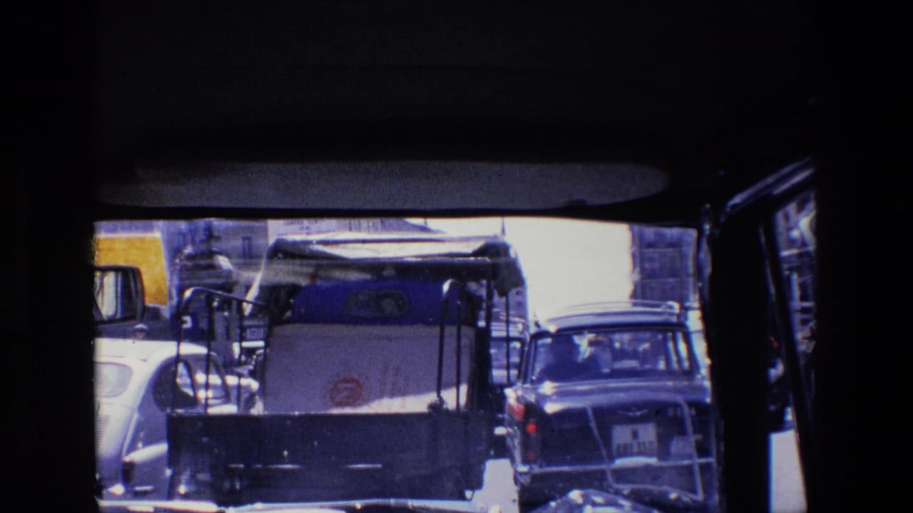 Traffic seen through a vehicle window with a white service vehicle and cars ahead.