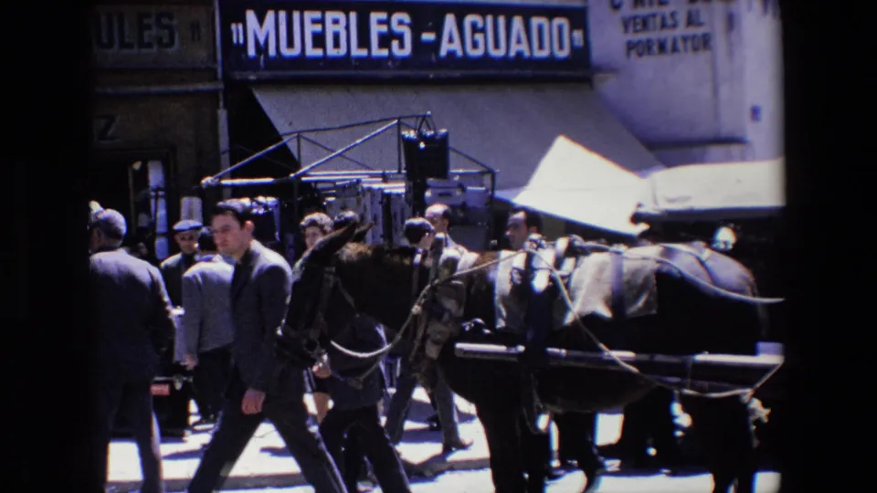 1967 Madrid street scene with a horse-drawn vehicle, pedestrians in suits, and visible commercial storefront signage.