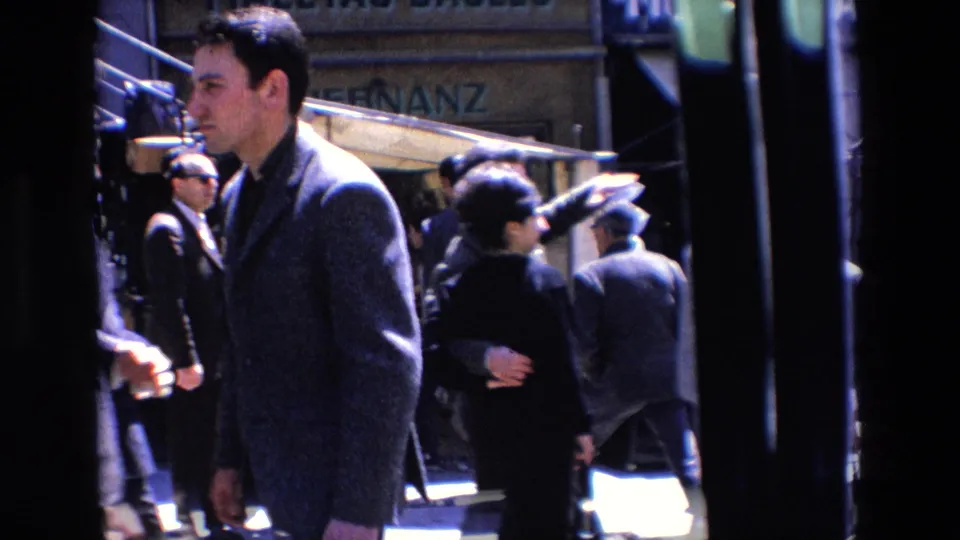 A suited pedestrian crosses the foreground of a busy 1967 Madrid commercial street with other pedestrians behind him.