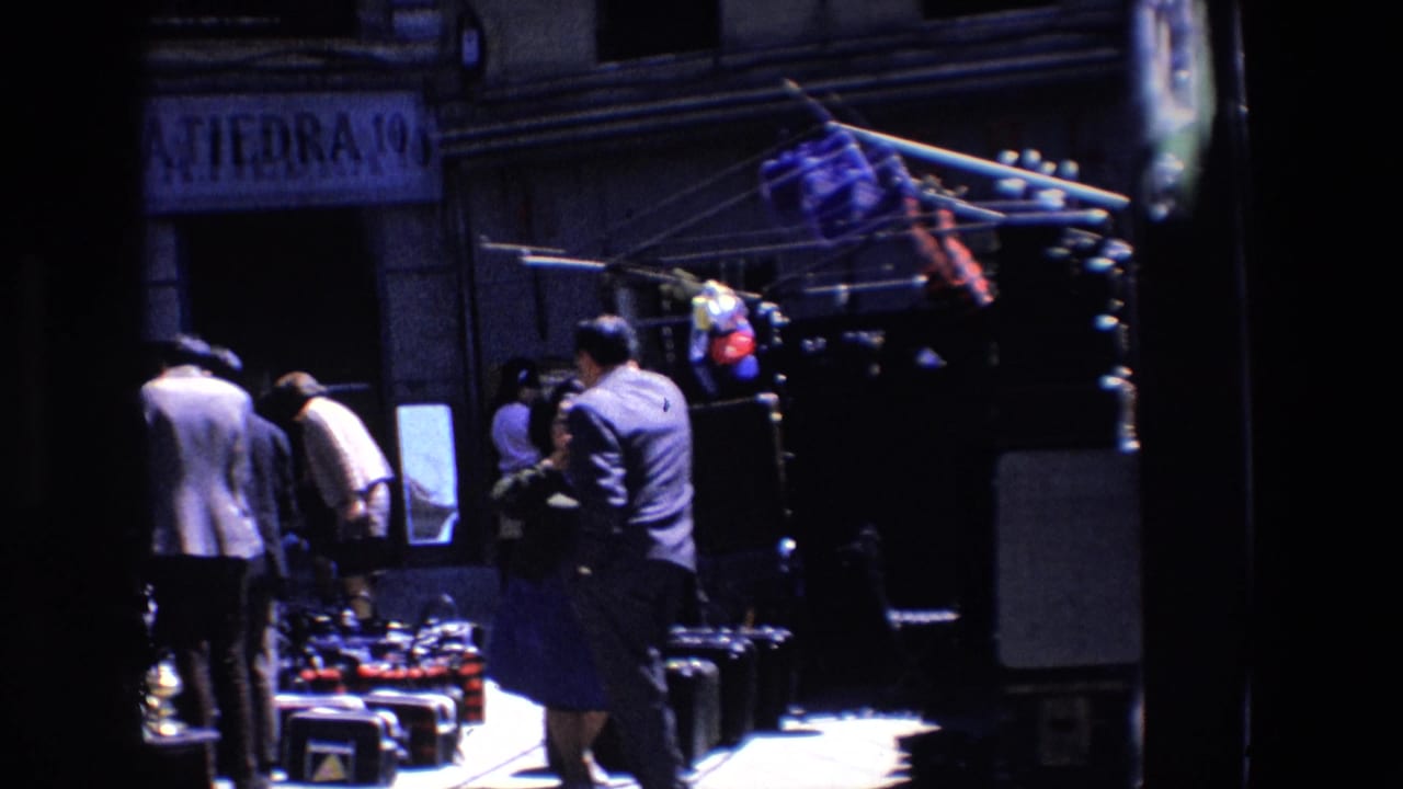 People stand near merchandise racks outside a shaded storefront.