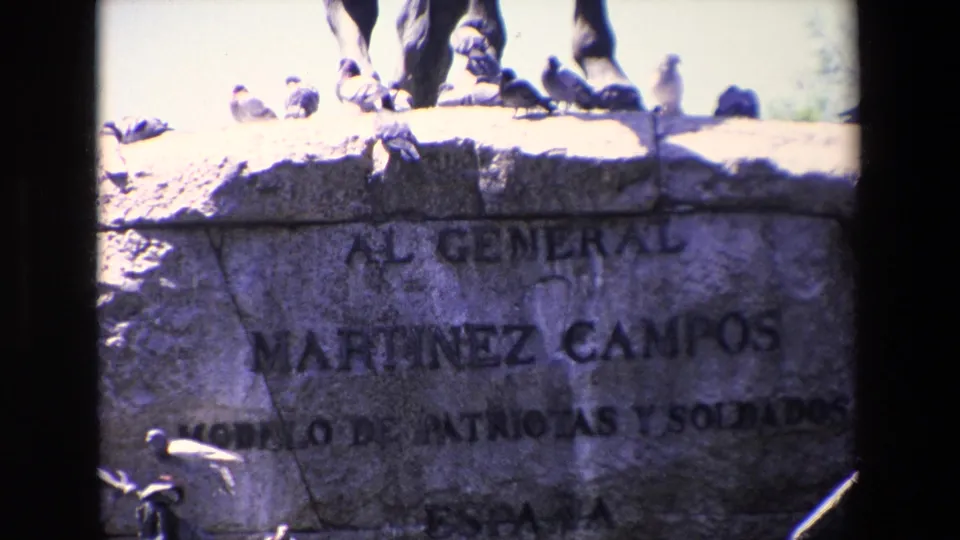A brighter close frame shows pigeons on the monument ledge and the readable General Martinez Campos inscription across the stone pedestal.