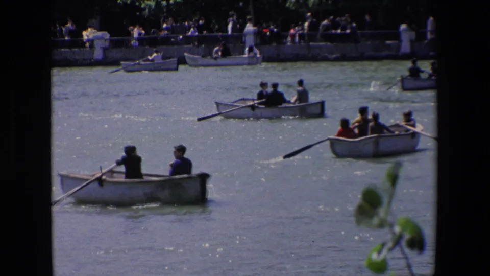 1967 Madrid frame with several rowboats crossing the water, including two people in a closer boat and more passengers near the far embankment.