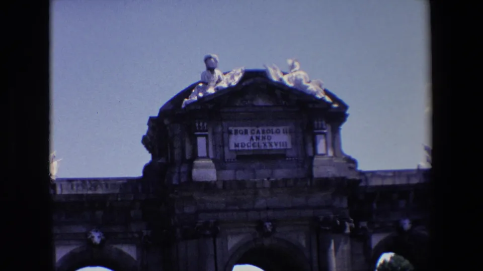 1967 Madrid frame tightening on the upper facade of Puerta de Alcala, with the King Charles III inscription panel and rooftop sculpture visible.