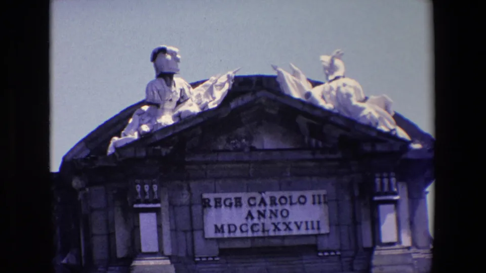 1967 Madrid close frame of Puerta de Alcala emphasizing the Latin dedication to King Charles III beneath sculptural figures on the roofline.
