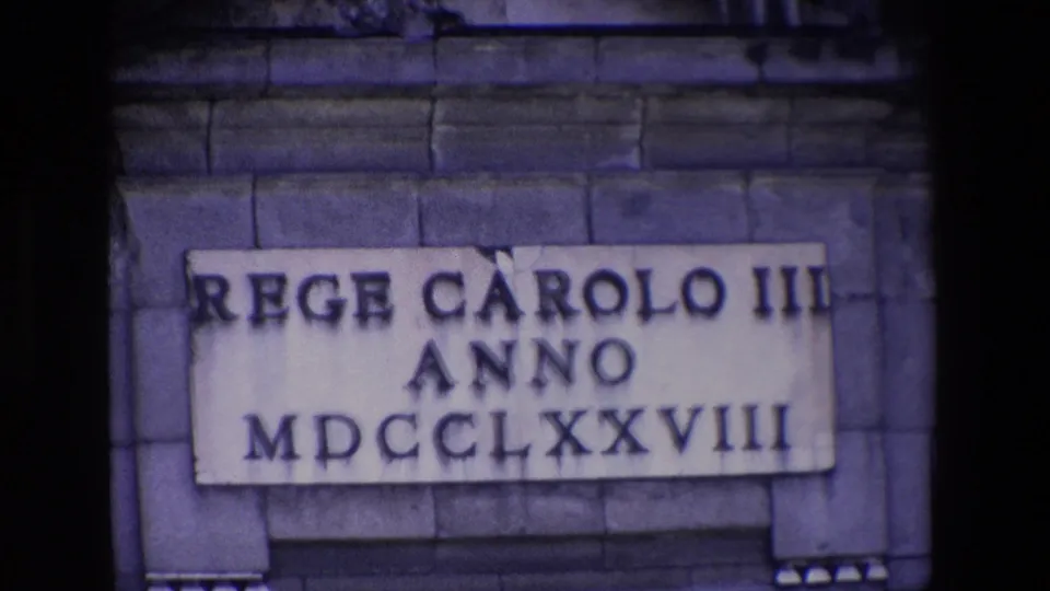 Madrid 1967 home-movie close-up of the rectangular stone plaque and Roman numerals, with the surrounding masonry filling most of the frame.