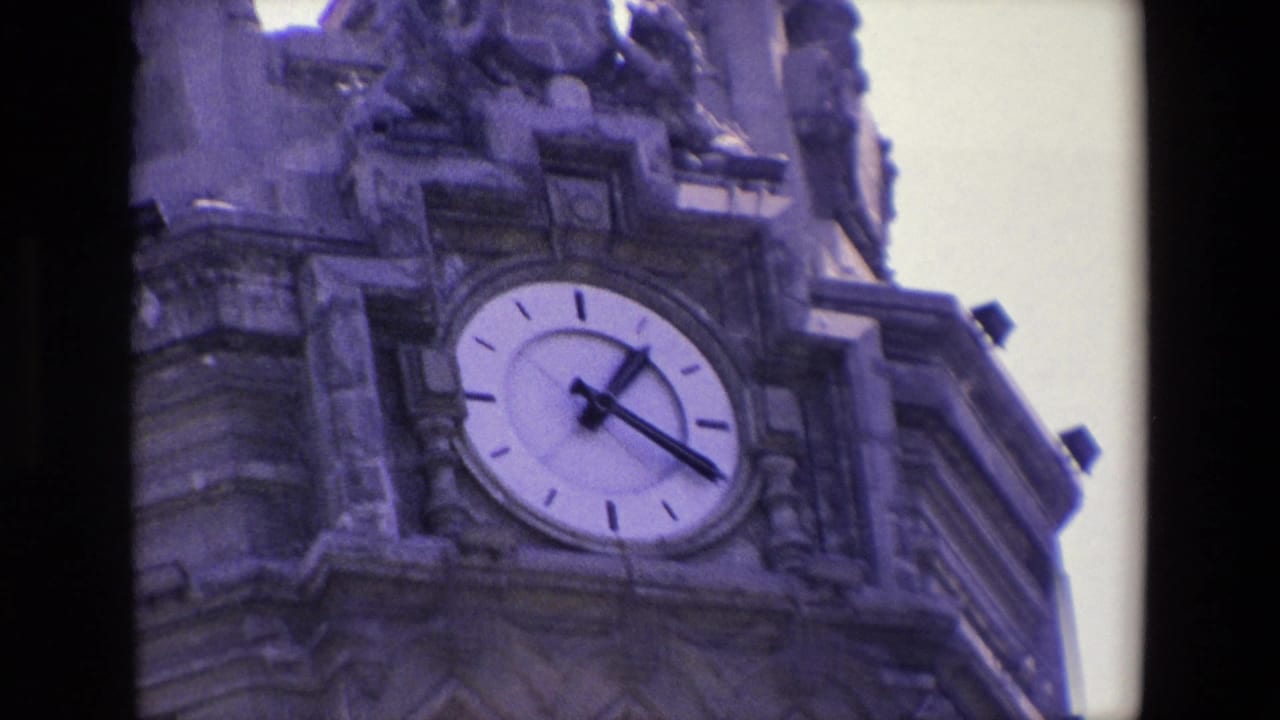 Closer view of the tower facade with a large round clock set into carved stonework.