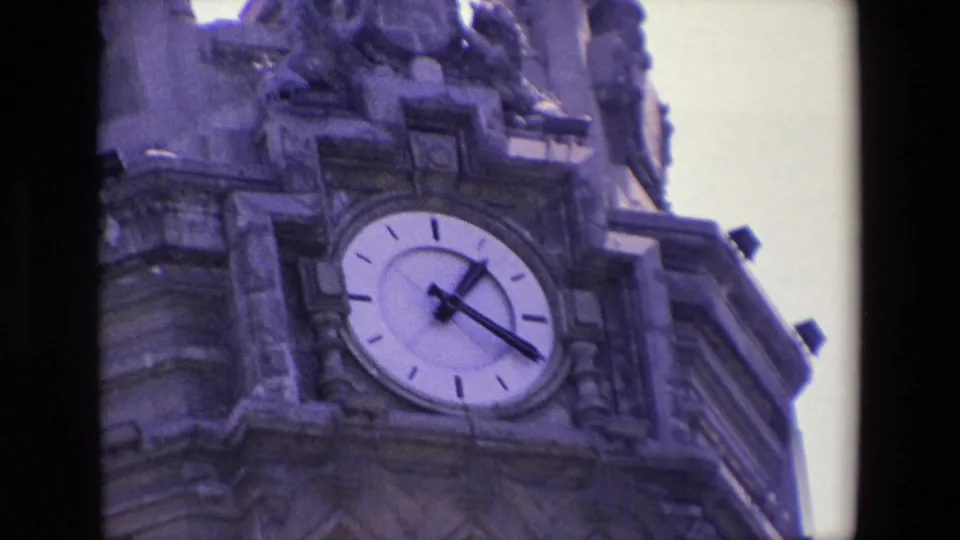 1967 Madrid 8mm frame focusing on the clock face and sculptural stone details of an ornate tower facade.