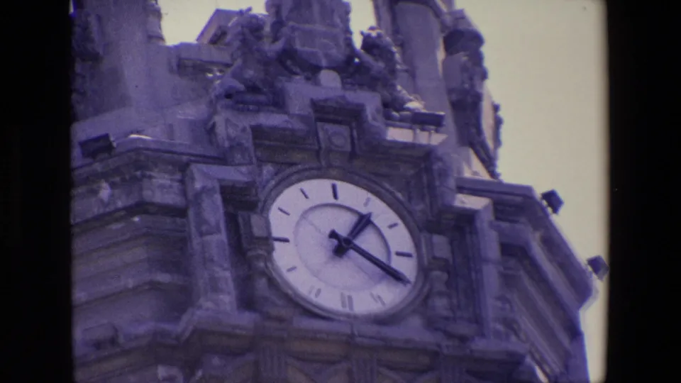 1967 Madrid 8mm frame with a tight handheld view of the analog clock face embedded in an ornate stone tower.