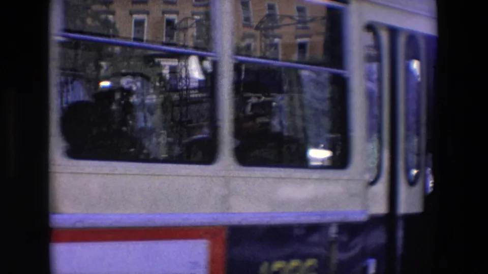 A double-decker bus passes close to the camera on a Madrid street, with windows, railings, and building facades visible behind it.