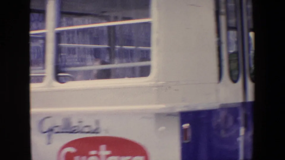 The side of a passing Madrid bus shows window rows and Galletas Cuetara branding as it moves through the frame.