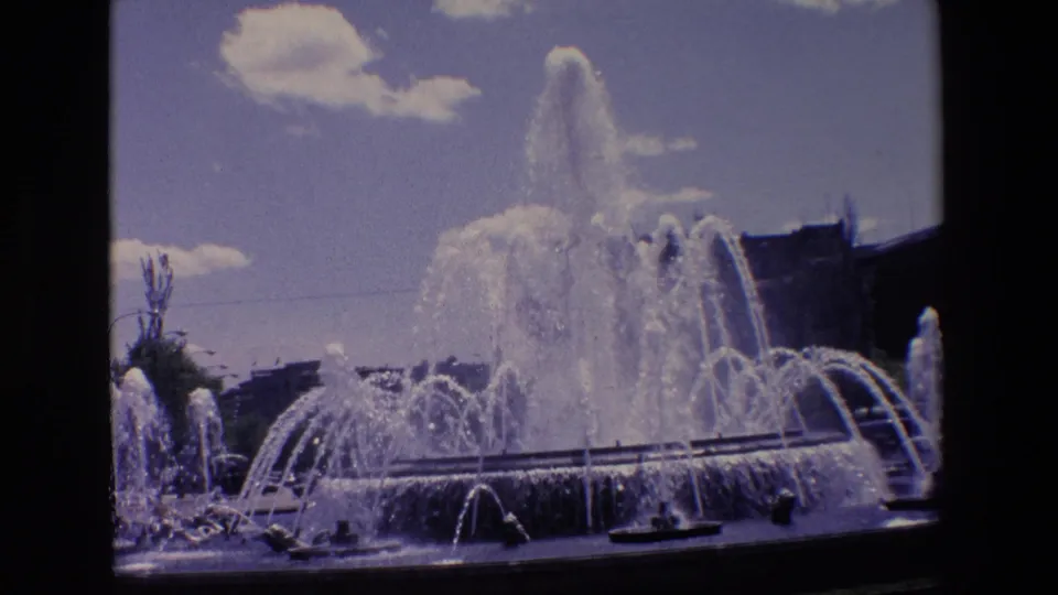 1967 Madrid home-movie still showing a closer view of the fountain basin, layered water streams, streetlights, and soft faded 8mm color.