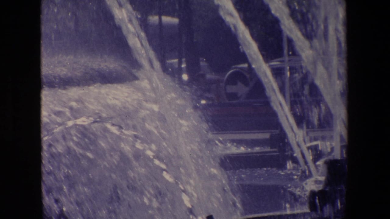 Heavy fountain spray with a bus or large vehicle behind it.