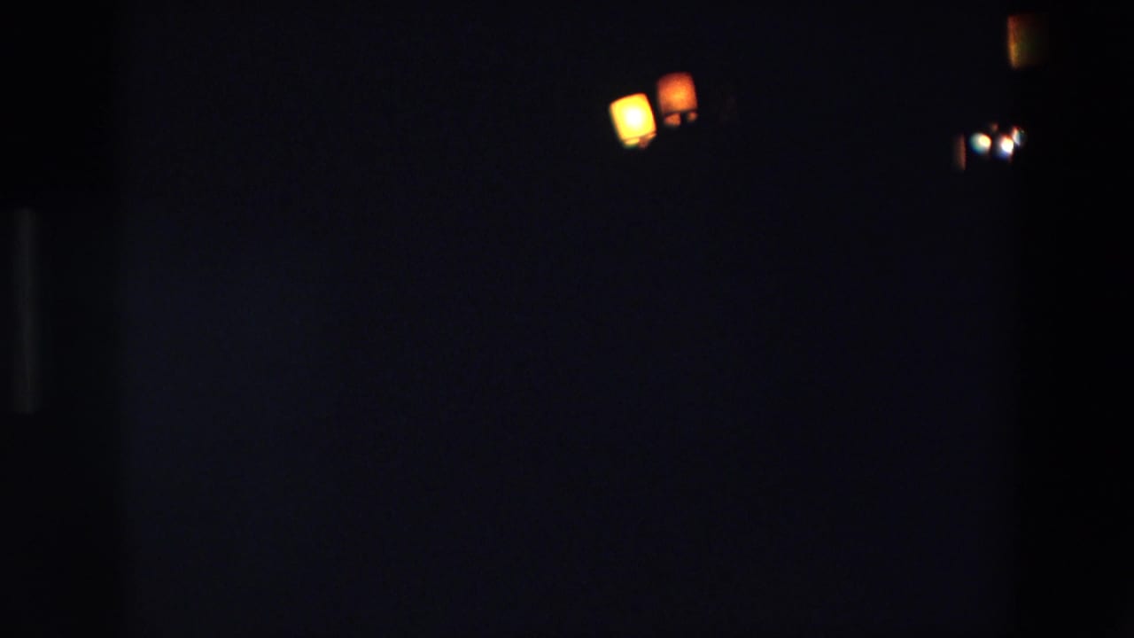 1967 Palermo 8mm frame showing several small warm lights against a dark sky, with little surrounding detail visible.