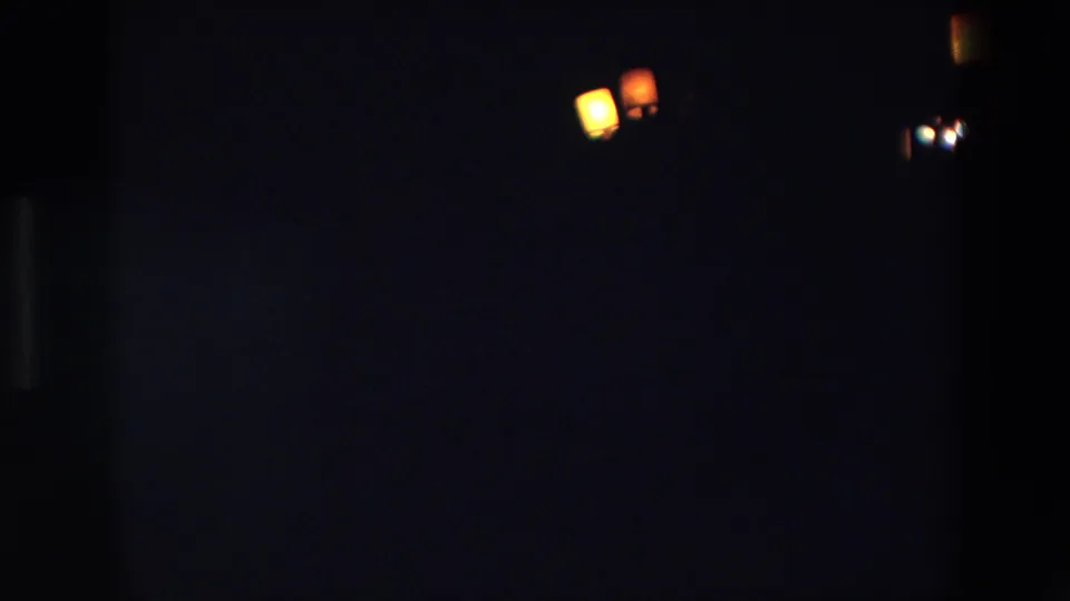 1967 Palermo 8mm frame showing several small warm lights against a dark sky, with little surrounding detail visible.