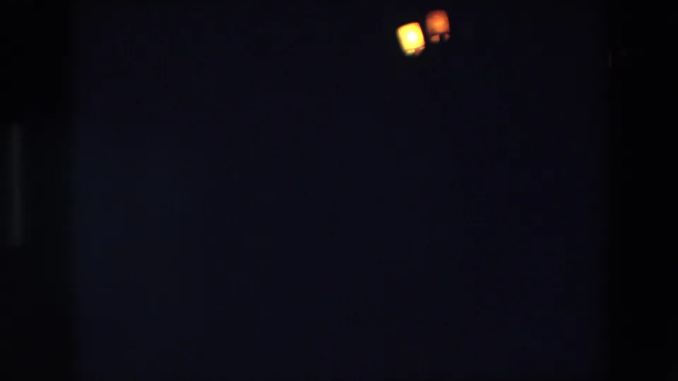1967 Palermo 8mm frame with a pair of warm glowing lights low in the composition and surrounding darkness obscuring context.
