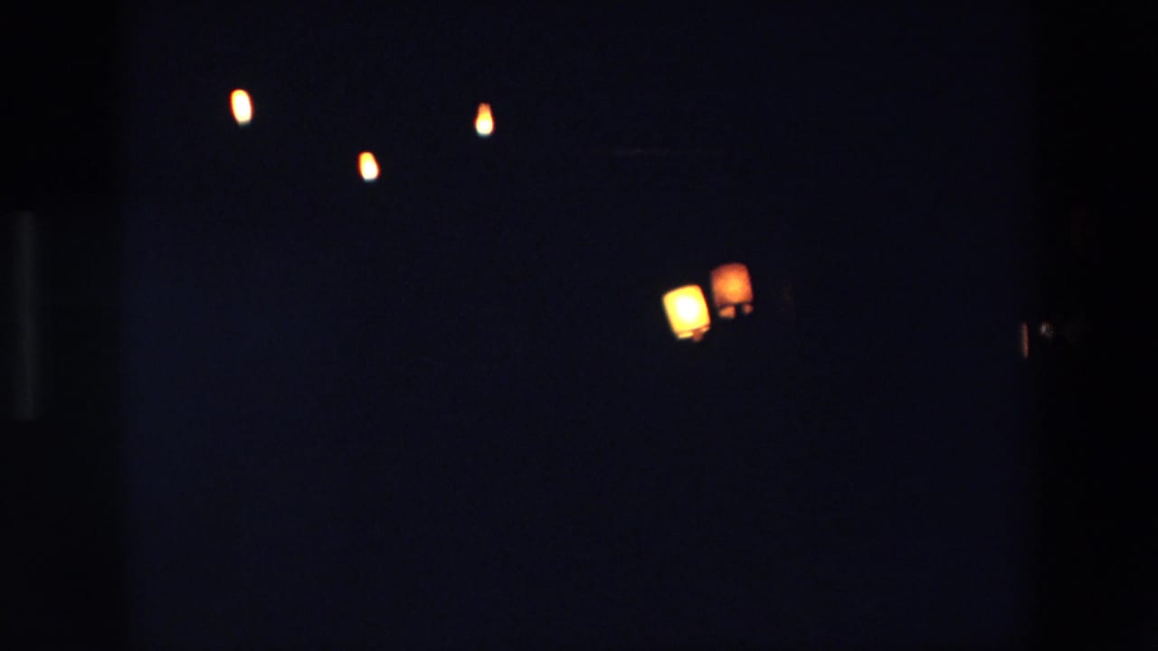 Palermo, Italy 1967 home-movie frame showing a very dark night sky with small glowing lantern-like lights softened by 8mm grain and low exposure.