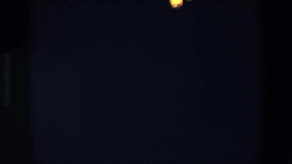 Underexposed 1967 Palermo night frame with two warm lantern-like points of light against a blue-black sky and visible 8mm texture.