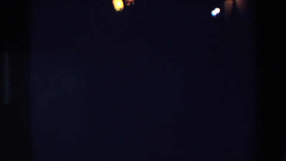 Palermo 1967 night frame showing a warm lantern-like glow and faint distant lights at the edge of a very dark 8mm image.
