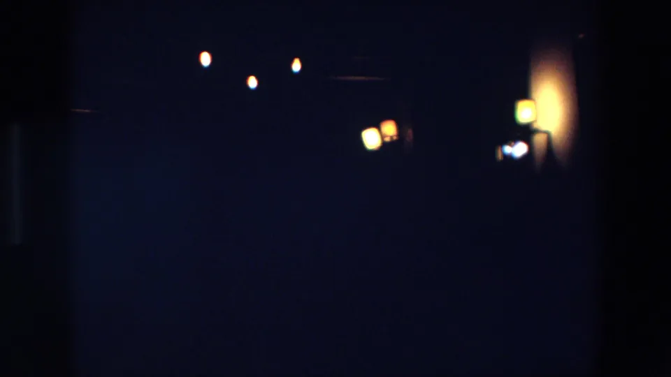 Low-light 1967 Palermo frame with out-of-focus warm lamps, faint highlights, and heavy shadow across the 8mm image.