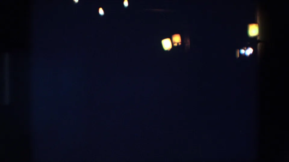 1967 Palermo night frame dominated by darkness, with a small right-side cluster of warm lights and grainy 8mm texture.