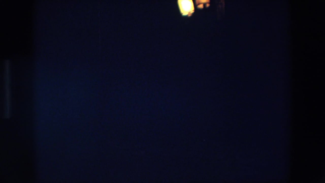 1967 Palermo 8mm frame with faint warm lights near the top edge and mostly dark, underexposed night surroundings.