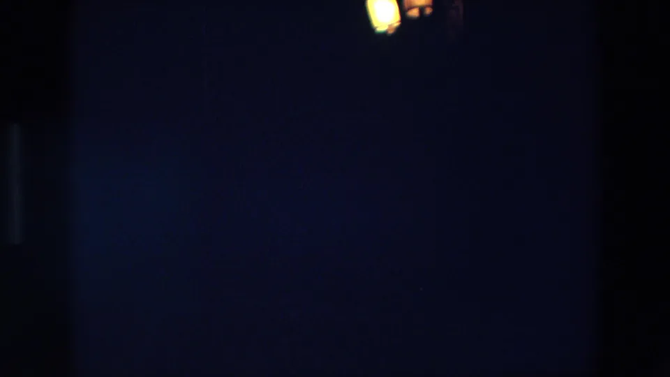 1967 Palermo 8mm frame with faint warm lights near the top edge and mostly dark, underexposed night surroundings.