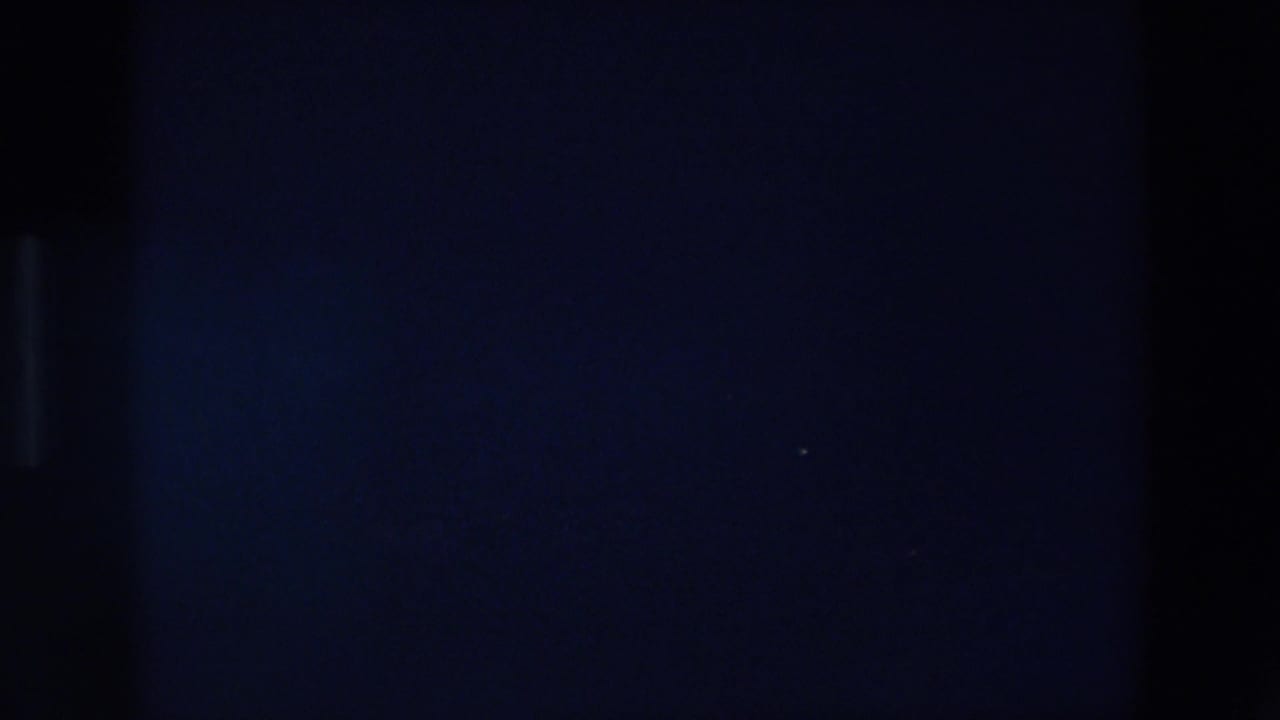Very dark frame with faint vertical shapes and minimal visible light.