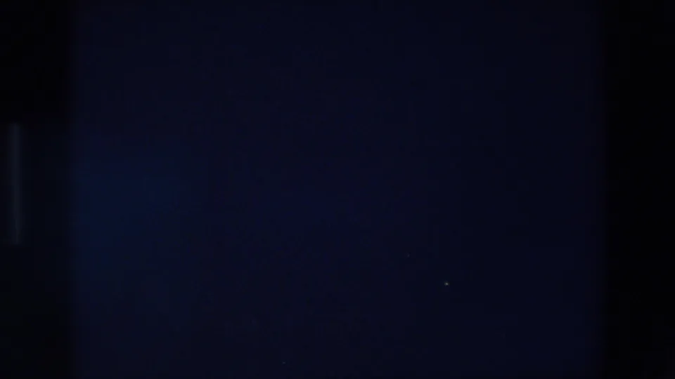 1967 Palermo 8mm frame showing a dim nighttime view with dark vertical shapes and a tiny light point in the distance.