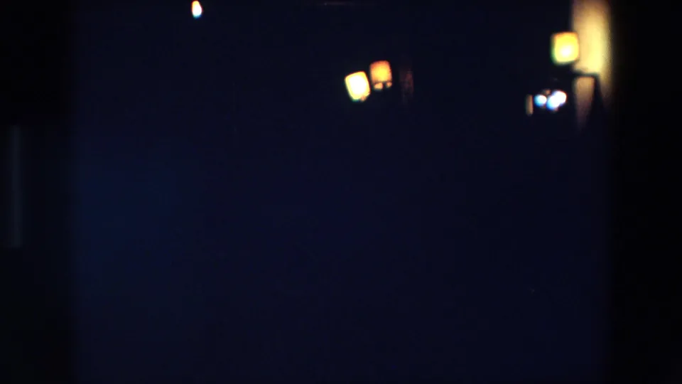 1967 Palermo 8mm frame with several warm lantern-like lights clustered at right against a dark, soft-focused night scene.