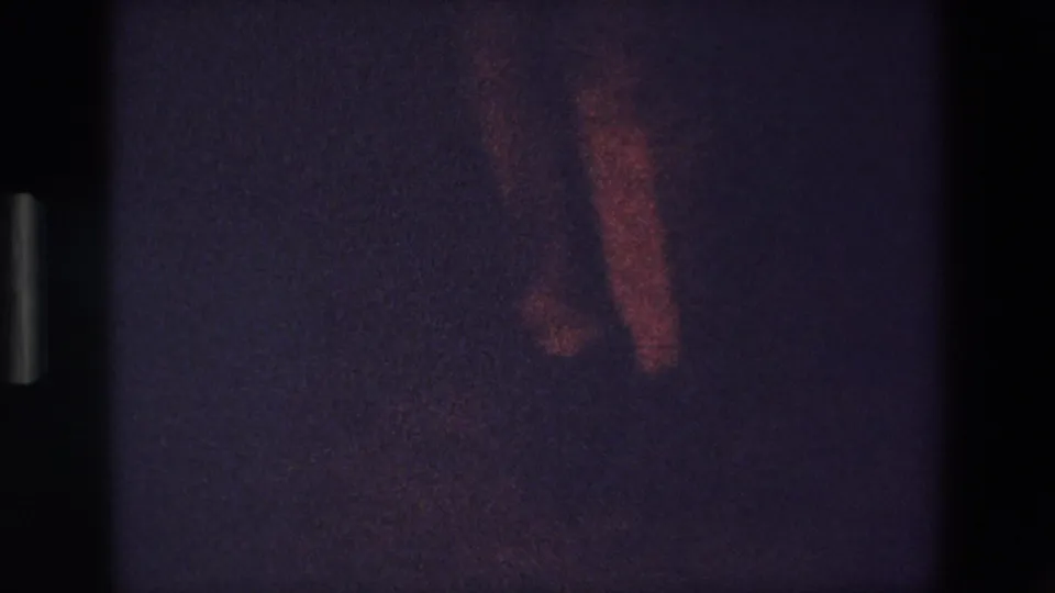 1967 Palermo 8mm frame with the dancer mostly obscured by darkness, showing a faint arm and legs with reddish exposure on the right side of the frame.