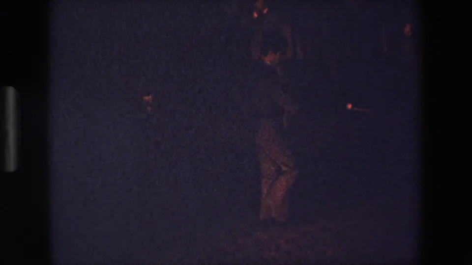 A shadowed figure is faintly visible near the lower area of a grainy 1967 Palermo night frame, with red highlights and a dark horizontal ground line.