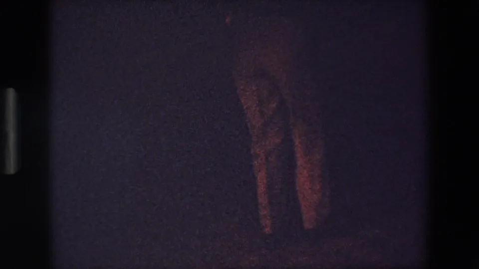 A standing person is more clearly outlined in a reddish, underexposed 1967 Palermo home-movie frame, with little surrounding street detail visible.
