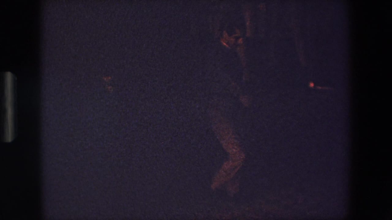 Man dancing in low light with one leg lifted or bent.