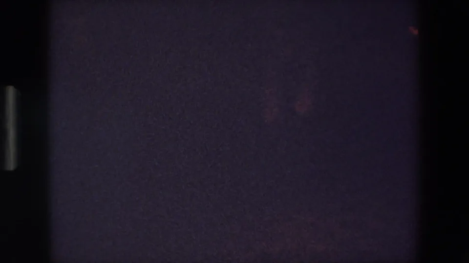 A very dark final frame from the 1967 Palermo clip shows the dancer partly at the right edge, with only faint leg movement and red glints visible through the grain.