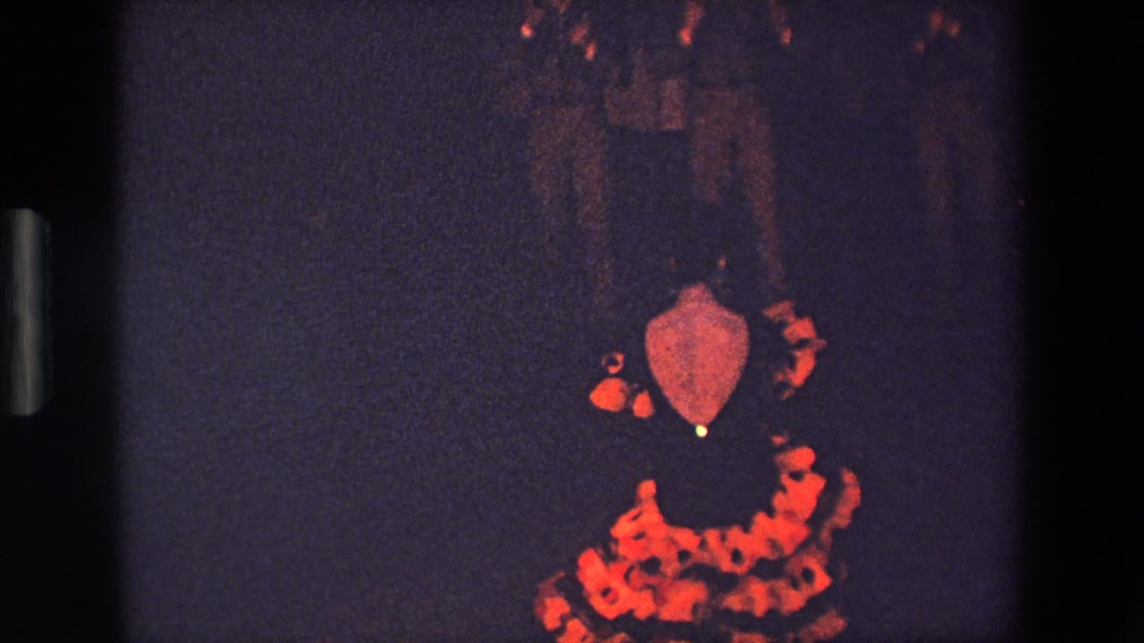 In this supplied 1967 Palermo 8mm frame, the dancer is seen mostly from behind, with the red patterned skirt standing out against a dark bar or dancehall setting.