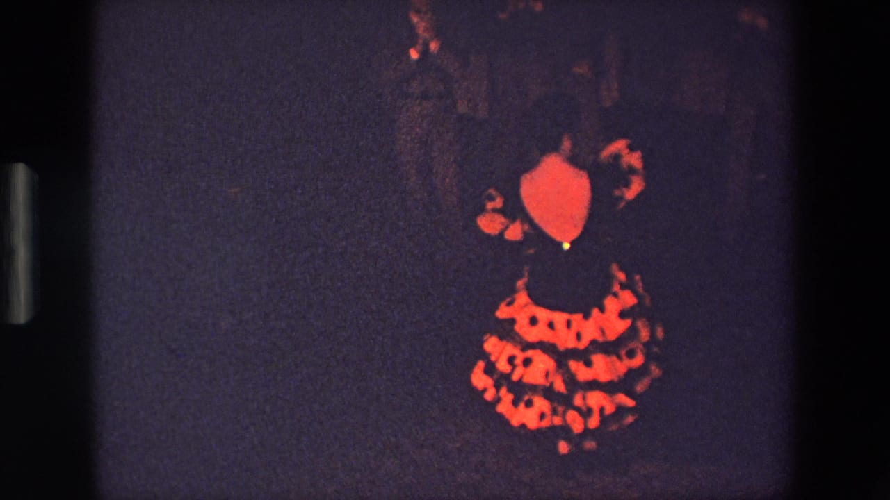 In this supplied 1967 Palermo 8mm frame, the dancer remains turned away, her red patterned dress illuminated against the dark room with little background detail visible.
