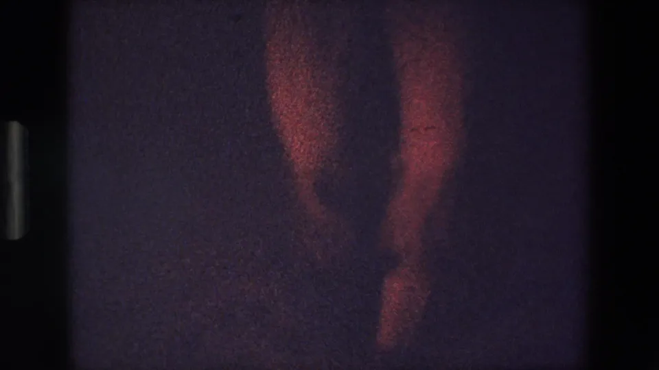 The frame emphasizes the dancer's legs and footwork beneath the red ruffled costume, with heavy grain and dim exposure from the 8mm scan.