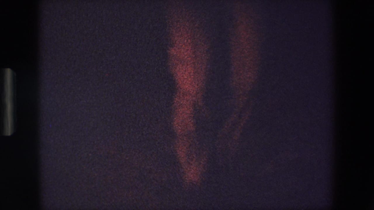 The final frame shows the dancer's lower body and red dress fading into underexposed stage light, preserving the handheld 8mm home-movie look.