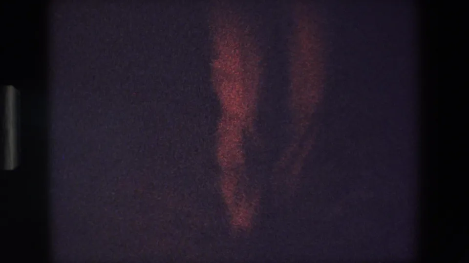 The final frame shows the dancer's lower body and red dress fading into underexposed stage light, preserving the handheld 8mm home-movie look.