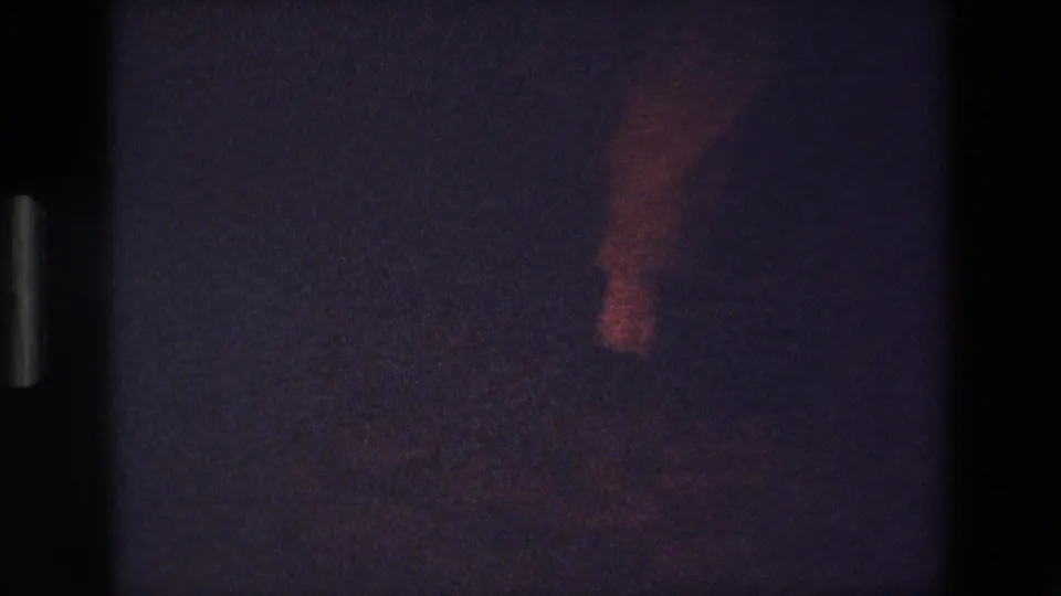 A low-light Palermo 1967 frame catches blurred lower-body movement, likely dancing feet, rendered with red tint, soft focus, and pronounced 8mm grain.