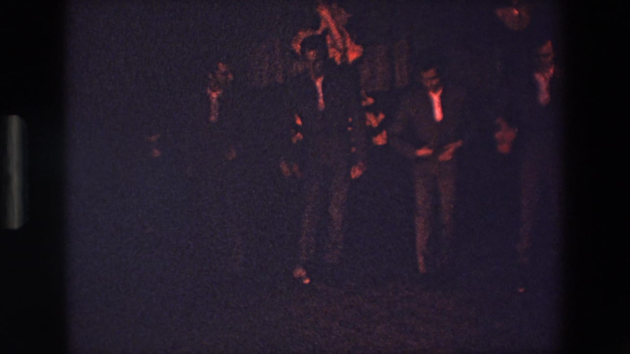 In Palermo, Italy, according to the clip metadata, several young men in suits appear to perform or dance in a dark club-like interior under warm red lighting.
