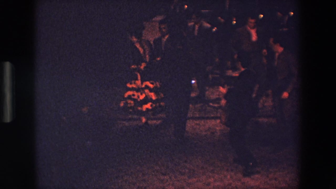 In metadata-supported Palermo, Italy, 1967, several men in dark suits appear to dance or gesture in a dim outdoor nighttime setting on grainy 8mm film.