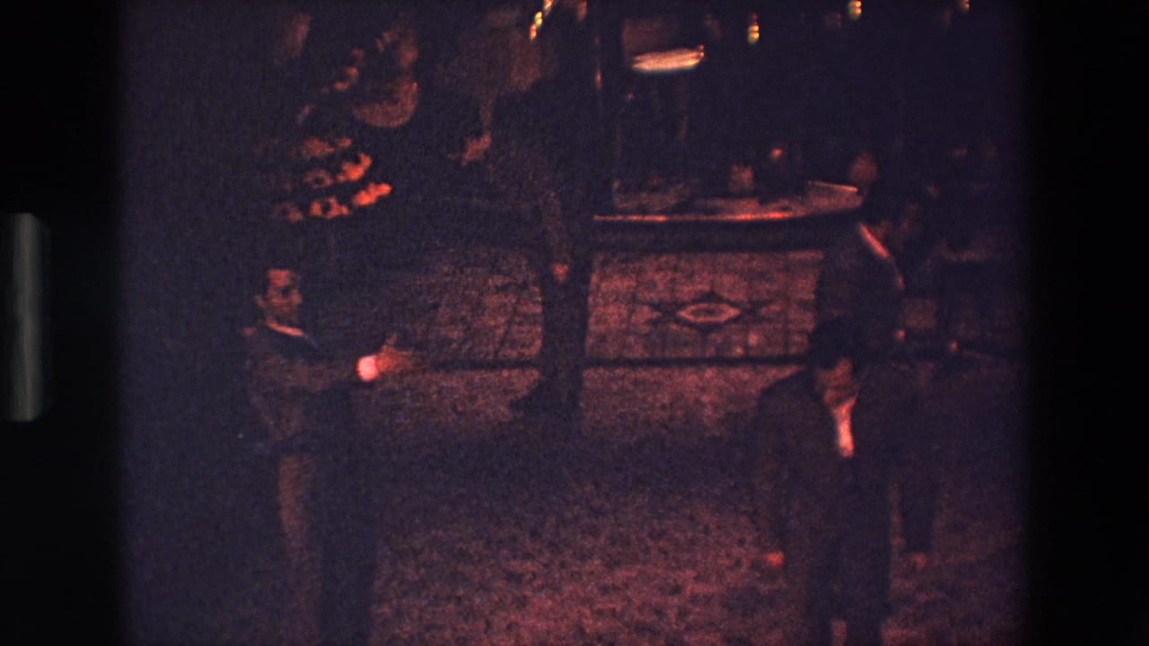 Near the end of the clip, suited men occupy the lower edge of the Palermo 1967 nighttime dance frame while other participants and faint lights remain visible in the background.