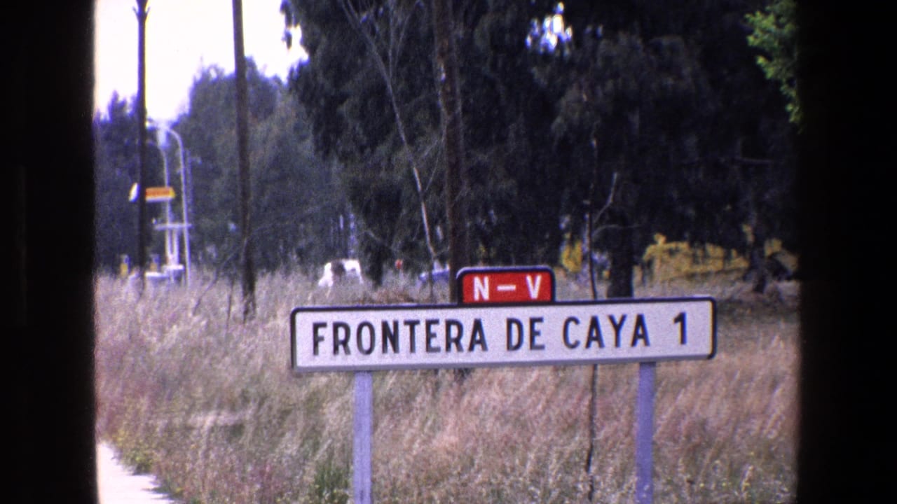 Roadside sign in a dry grassy area with trees, utility poles, and a distant vehicle behind it.