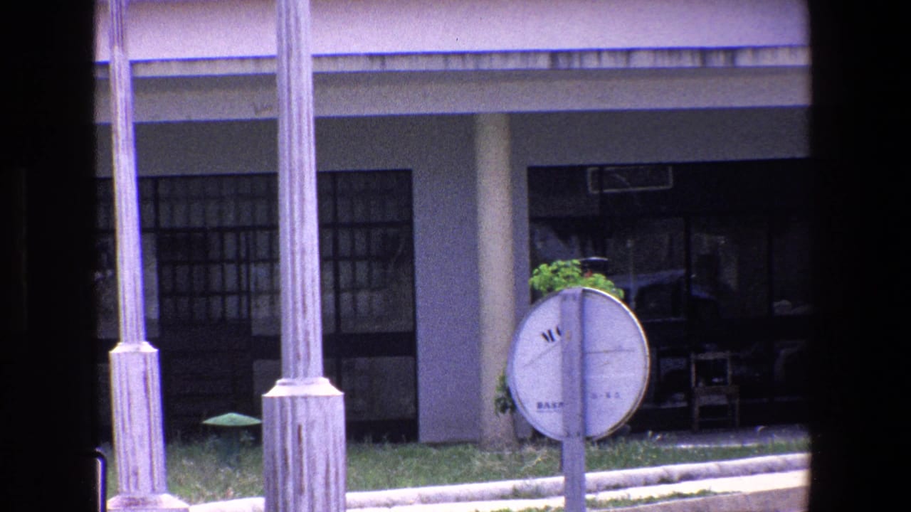 Building entrance and circular sign partly obscured by a dark frame, with no clear person centered in view.