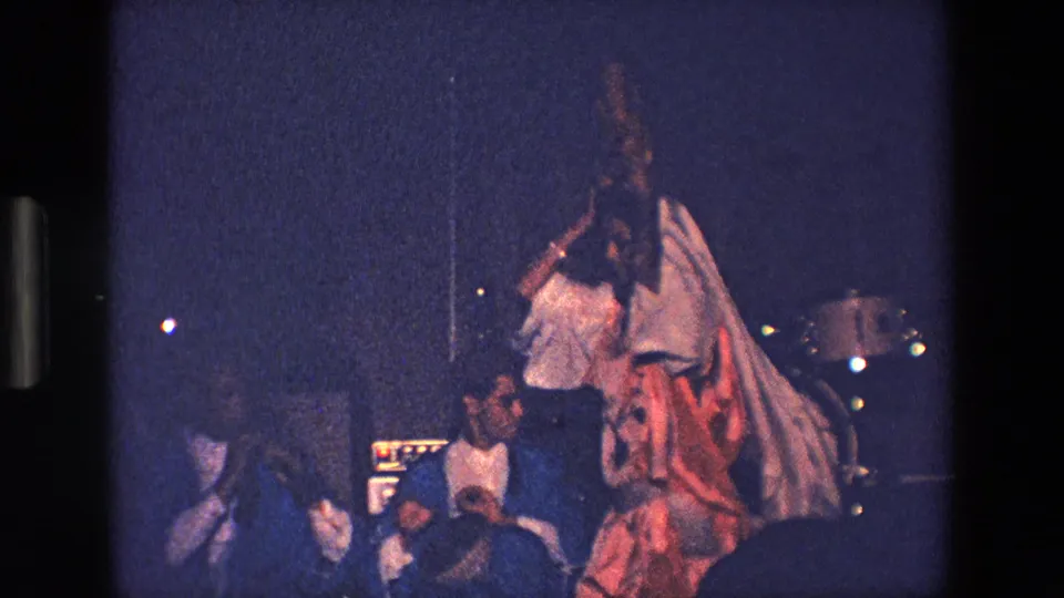 1967 Palermo nighttime festival footage showing a woman in white robes and headdress dancing near seated or standing spectators and possible band equipment.