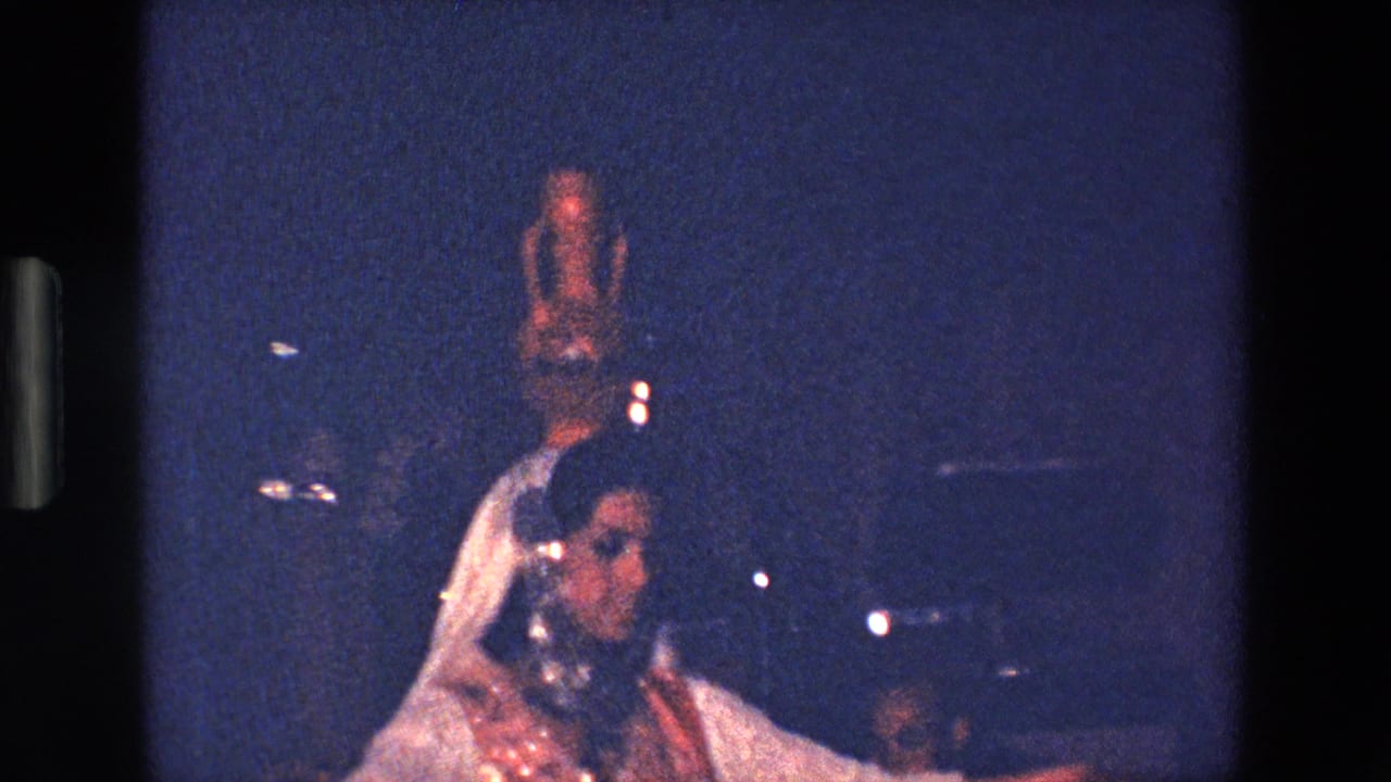 Performer turns with a tall vessel balanced on her head as another figure appears nearby.