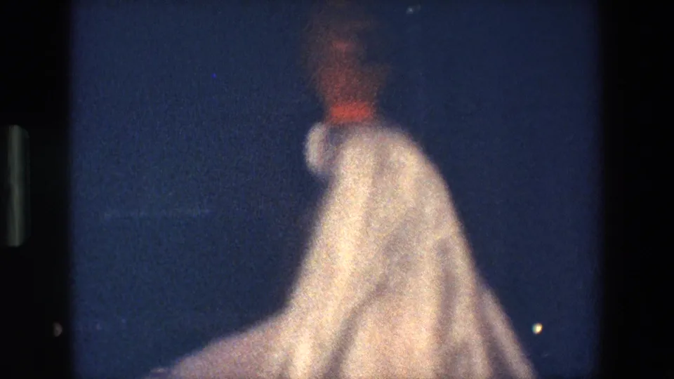 The final frame shows the performer from a rear or side angle in Palermo, with her light costume and the balanced vessel blurred by motion and low-light 8mm exposure.